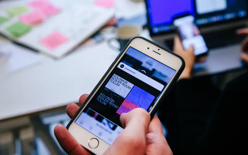 A hand holding a phone with a business website open